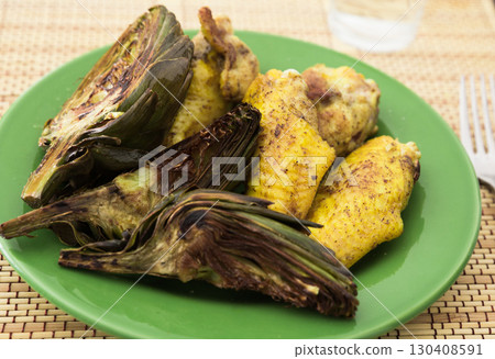 cooked fried chicken wings and halves artichokes on green plate cooked fried chicken wings and halves artichokes on green plate 130408591