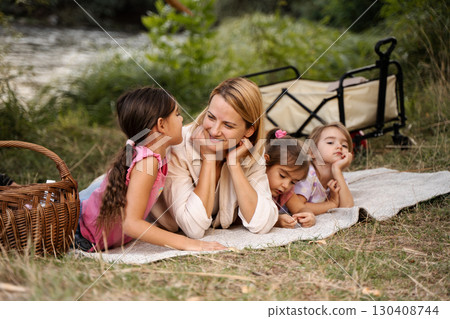 Mother and daughters enjoying a picnic by the river 130408744