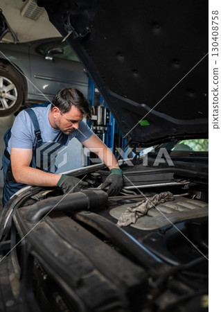 Mechanic repairing car engine in auto repair shop 130408758