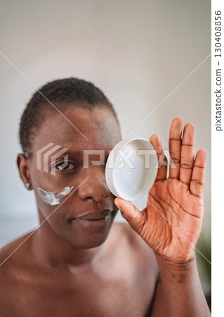Young woman applying moisturizing cream on her face Young woman applying moisturizing cream on her face 130408856