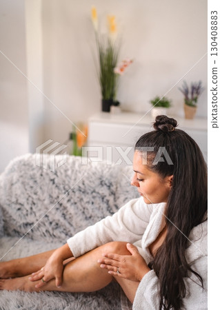 Young woman applying moisturizing cream on her legs at home Young woman applying moisturizing cream on her legs at home 130408883
