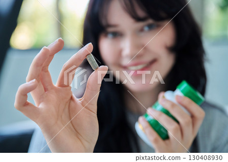 Close up of herbal phyto capsule and bottle in hands of young smiling woman 130408930