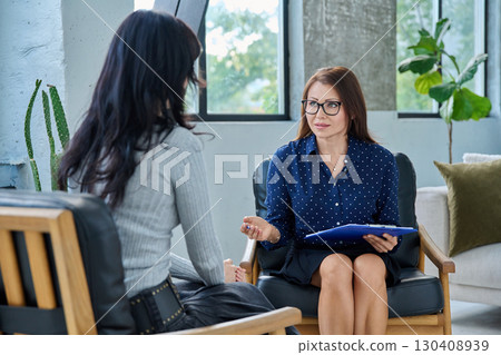 Middle aged professional female psychologist, counselor working with young woman 130408939