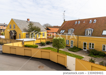 Yellow residential building with a yard on a sunny day. 130409481