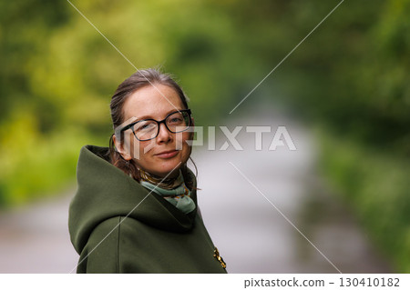 Woman enjoying a peaceful moment outdoors in a park on a sunny day surrounded by greenery Woman enjoying a peaceful moment outdoors in a park on a sunny day surrounded by greenery 130410182
