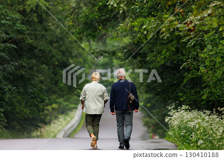 Couple walking hand in hand along a peaceful forest path during a warm summer afternoon 130410188