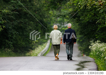 Couple walking hand in hand along a peaceful forest road on a cloudy day 130410190