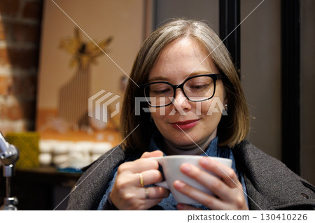 Woman enjoying a warm drink in a cozy cafe during a calm afternoon with brick wall decor Woman enjoying a warm drink in a cozy cafe during a calm afternoon with brick wall decor 130410226