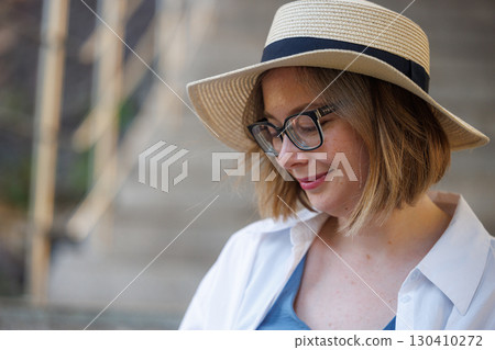 Enjoying a sunny day outdoors while wearing a stylish hat and glasses and feeling relaxed in a quaint location 130410272