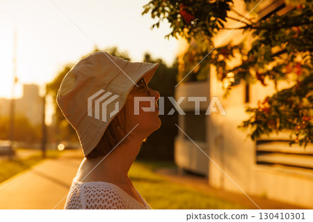 Person enjoying golden hour light while admiring a tree in an urban setting Person enjoying golden hour light while admiring a tree in an urban setting 130410301