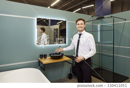 Portrait of happy smiling young salesman standing in plumbing shop and looking cheerful at camera. Portrait of happy smiling young salesman standing in plumbing shop and looking cheerful at camera. 130411051