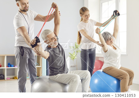 Doctor And Trainer Leading Elderly Couple In Rehabilitation Session 130411053