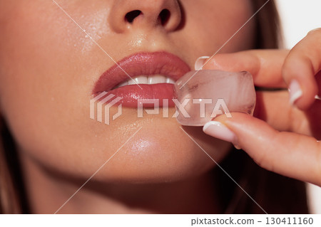 Female lips touching ice cube with natural gloss and cooling freshness Female lips touching ice cube with natural gloss and cooling freshness 130411160