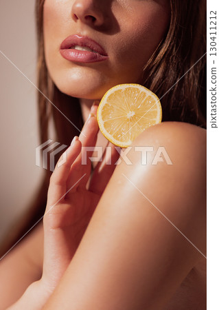 Woman lips with lemon slice against shoulder in natural skincare aesthetic Woman lips with lemon slice against shoulder in natural skincare aesthetic 130411212