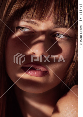 Female face with expressive lips and soft shadows creating dramatic minimal aesthetic 130411241