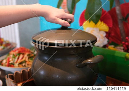 Hand touching pot reaches for the hot electric stove. Child safety at the stove.  130411259