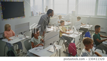 Teacher Helping Boys and Girls in Learning Coding During Programming Lesson 130411320
