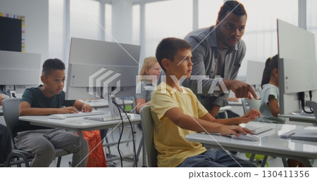 Primary School Students Working on Computers. Teacher Guiding Young Boy in Studying Programming 130411356