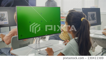Elementary School Girl Using Computer with Green Screen During Digital Art Lesson 130411389