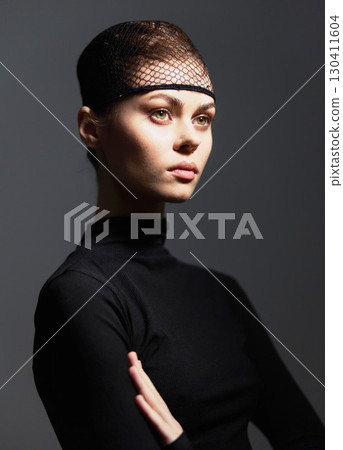 Thoughtful young woman wearing a stylish black outfit, looking away with a contemplative expression. Fashion and beauty concept with soft lighting. 130411604