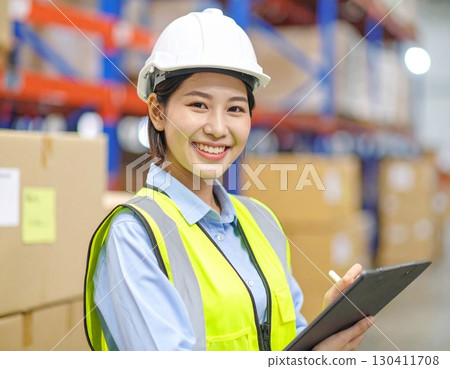 A working Japanese woman checking packaging and inventory at a factory 130411708