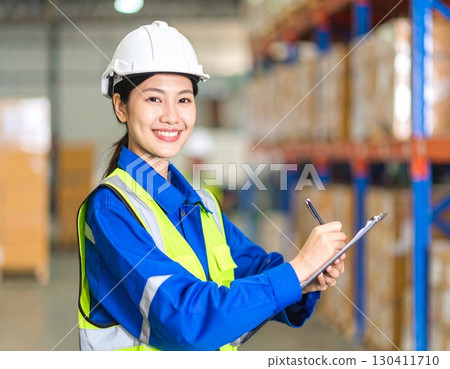 A working Japanese woman checking packaging and inventory at a factory 130411710
