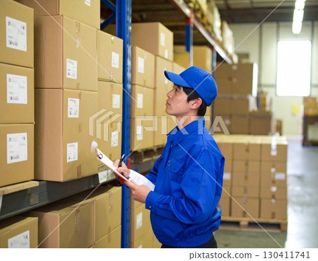 A man in work clothes who manages inventory in a warehouse 130411741