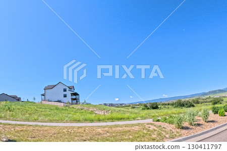 A residential neighborhood on a gentle hillside in Castle Rock, Colorado with green grass and homes visible in the background. The photo is taken under bright daylight with a wide perspective. A residential neighborhood on a gentle hillside in Castle Rock, Colorado with green grass and homes visible in the background. The photo is taken under bright daylight with a wide perspective. 130411797