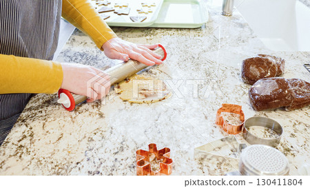 Using an adjustable rolling pin to roll out gingerbread cookie dough on the elegant marble counter in a modern kitchen, getting ready for festive holiday baking. Using an adjustable rolling pin to roll out gingerbread cookie dough on the elegant marble counter in a modern kitchen, getting ready for festive holiday baking. 130411804