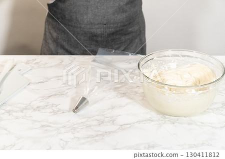 Transferring the homemade cream cheese frosting into a piping bag, ready to create beautiful and delicious decorations. 130411812