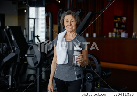 An elderly woman in a gym with a water bottle and towel An elderly woman in a gym with a water bottle and towel 130411856