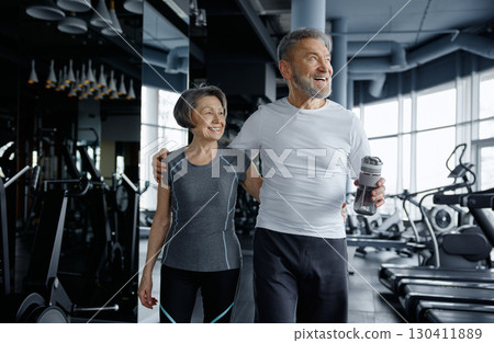 A man and a woman are happily posing for a picture together in a gym A man and a woman are happily posing for a picture together in a gym 130411889