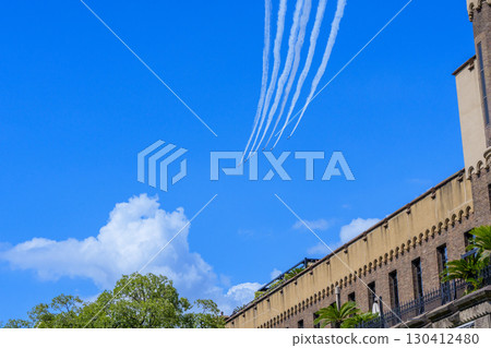 藍色衝擊波飛機以弧線飛過藍天和歷史建築景觀 130412480