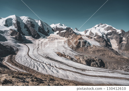 High peaks of Piz Bernina and Piz Palu rise dramatically above the Pers Glacier in the Bernina Range. The rugged alpine landscape showcases the beauty of the Swiss Alps in Graubunden. 130412610