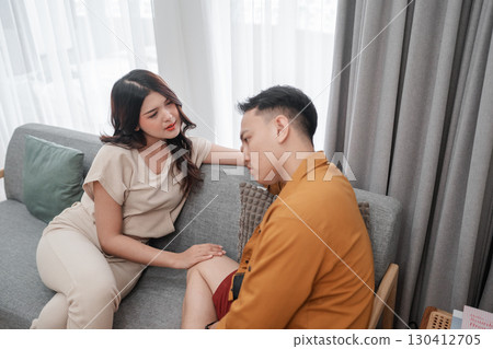 A couple shares an intimate conversation on a cozy sofa, exchanging affection A couple shares an intimate conversation on a cozy sofa, exchanging affection 130412705