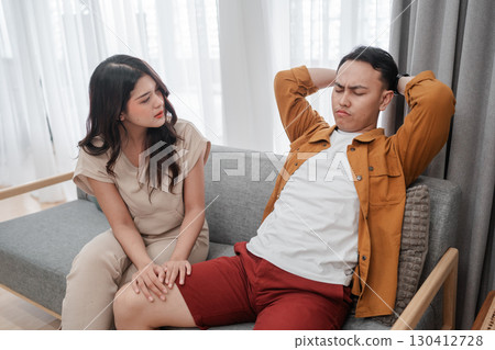 A couple discussing emotions on a cozy sofa in a bright living room, fostering connection 130412728
