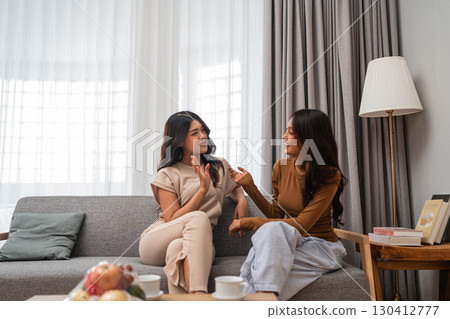 Two close friends have a casual conversation in a cozy living room, deepening their bond Two close friends have a casual conversation in a cozy living room, deepening their bond 130412777