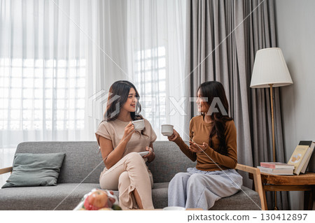 Friends enjoy coffee together in a cozy living room, bonding over happiness Friends enjoy coffee together in a cozy living room, bonding over happiness 130412897