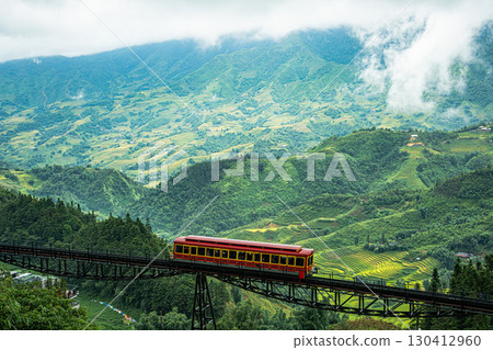 Red mountain train crossing a bridge in misty Sapa, Vietnam 130412960