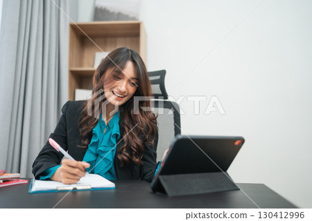 A Professional Woman Working with a Tablet and Notebook in a Modern Office A Professional Woman Working with a Tablet and Notebook in a Modern Office 130412996
