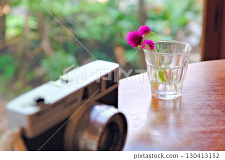 一個裝滿水的玻璃花瓶和一台底片相機 一個裝滿水的玻璃花瓶和一台底片相機 130413152