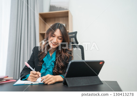 A Dedicated Businesswoman Engaged in Remote Work at a Modern Office Environment A Dedicated Businesswoman Engaged in Remote Work at a Modern Office Environment 130413278