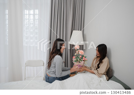 Heartwarming Moment: Two Friends Sharing a Beautiful Bouquet in a Cozy Room 130413486