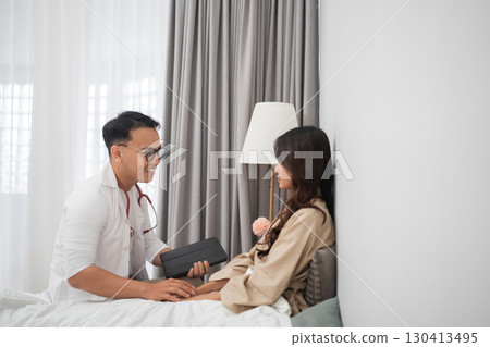 Medical consultation in a cozy bedroom setting with healthcare professional 130413495