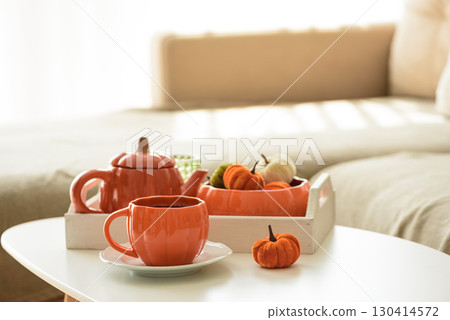 Autumnal living room decor with pumpkins, teapot, tea cup and cozy blankets. 130414572