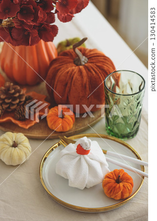 Thanksgiving table setting with decorative pumpkins, candles and string lights on white wooden table 130414583