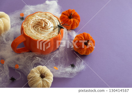 Halloween themed flat lay with a pumpkin latte, decorative pumpkins and spiderwebs on a purple background. Halloween themed flat lay with a pumpkin latte, decorative pumpkins and spiderwebs on a purple background. 130414587
