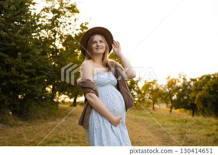 Smiling pregnant woman in summer dress and hat outdoors 130414651