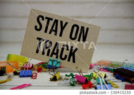 Stay On Track text on paper card with stationary on wooden background Stay On Track text on paper card with stationary on wooden background 130415230