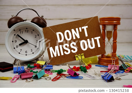 Don't miss out text on paper card with alarm clock and stationary on wooden background Don't miss out text on paper card with alarm clock and stationary on wooden background 130415238